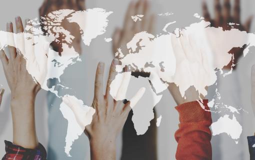 World map superimposed over raised hands