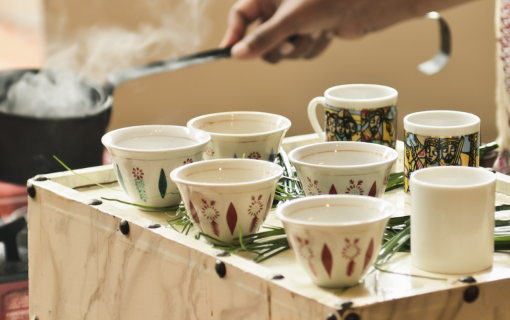 Hands preparing traditional Ethiopian coffee Ceremony with cups and steaming pot.