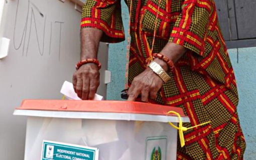 A man puts a paper ballot into a ballot box.