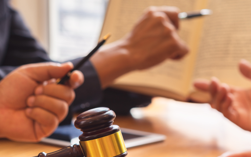 hands holding pens and paper. a judges gavel is in view.