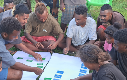A group of young people sit together playing the Rights and Responsibilities game together.