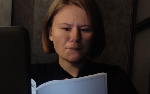 Anastasiia’s in a dark room reading.