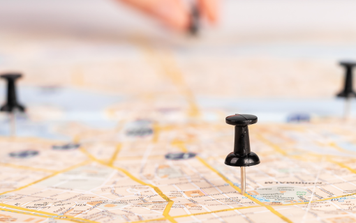 Push pins laid out on a road map. hand in the background with additional pin.