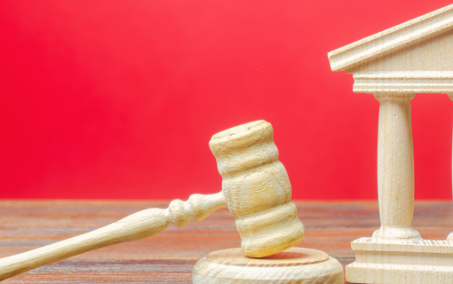 red background, wooden toy structure of a government building, wooden toy gavel.