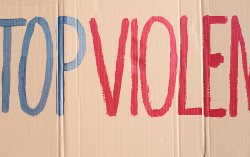 Protest sign reads Stop Violence in blue and red.