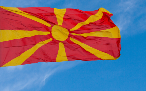 Flag of North Macedonia flying in blue sky.