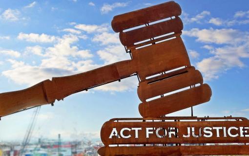 Machinery with sky in the background shaped like a gavel that reads Act for Justice