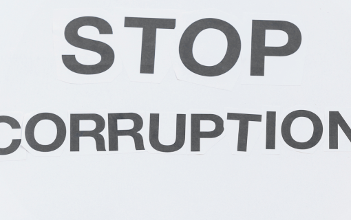woman holding placard that says stop corruption outdoors. photo credit pixelshot