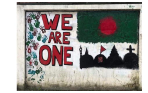Mural with the phrase 'WE ARE ONE' painted in large letters, surrounded by handprints in various colors. Below the text, a silhouette skyline featuring a mosque, a temple, and a church, set against a red circle backdrop, symbolizing unity and diversity.