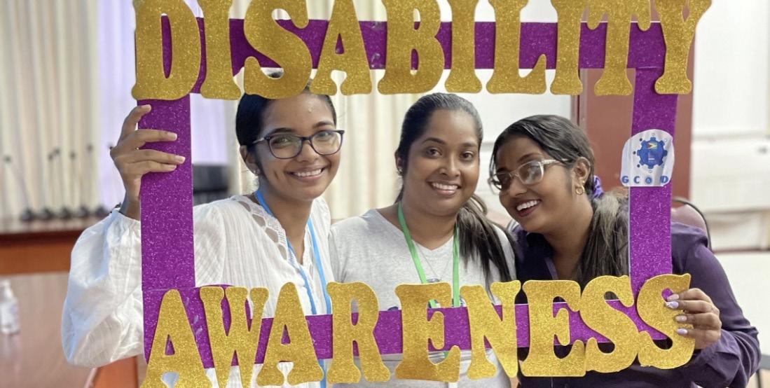 Alt text: Three women from Guyana smile at the camera. They are holding up a purple photo frame that reads “Disability Awareness” in gold letters. This is an example of alt-text for an image. Learning Series on Disability-Inclusive Election Technology