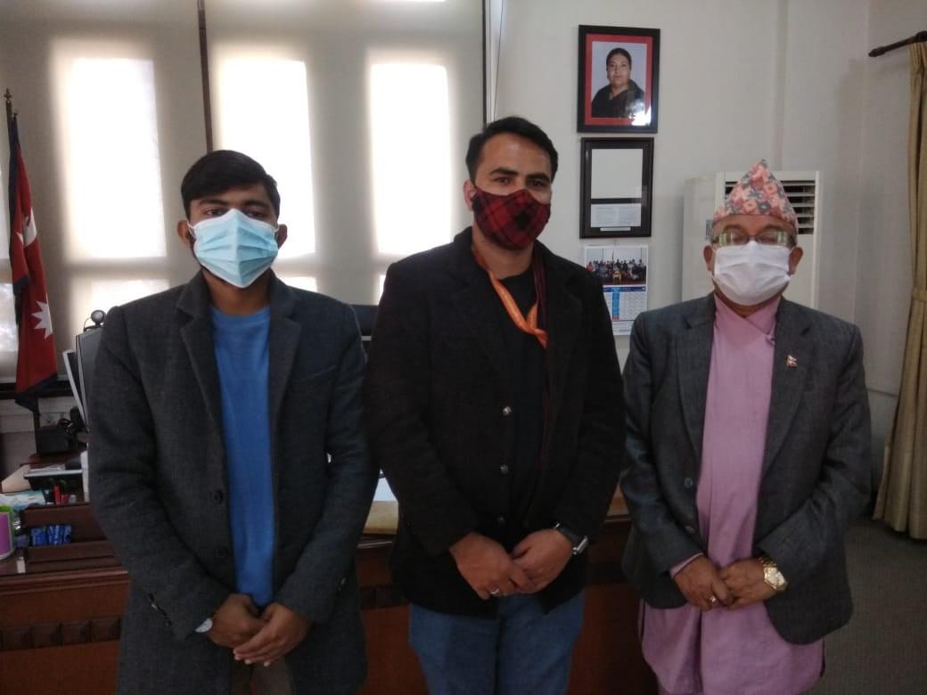 Three men stand side by side, posing for a picture, in an office.