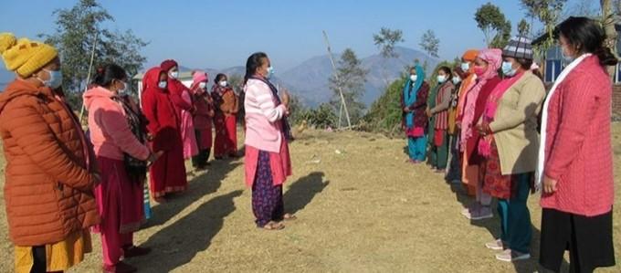 Two rows of people wearing different shades of pink stand outside facing each other.