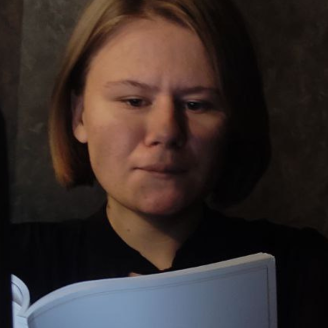 Anastasiia’s in a dark room reading.