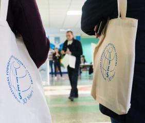 Two people walking with IFES branded tote bags