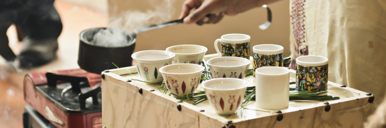 Hands preparing traditional Ethiopian coffee Ceremony with cups and steaming pot.