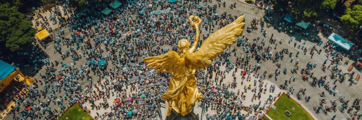 High Angle View Of Crowd Marching On Independence monument in Mexico City.