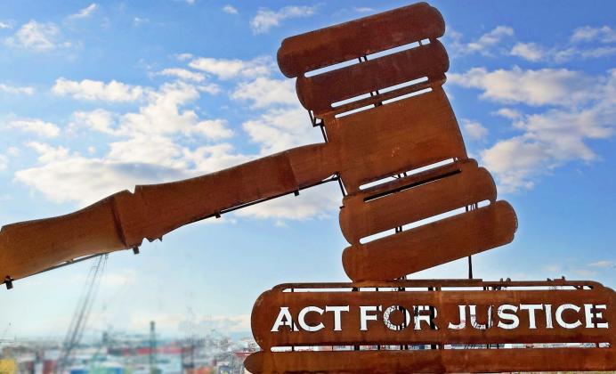 Machinery with sky in the background shaped like a gavel that reads Act for Justice