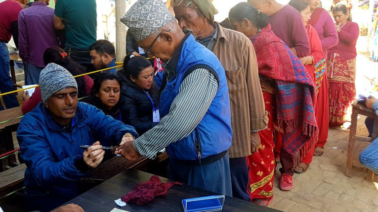 Voters queue to receive their ballots and have their fingers marked with indelible ink in Bhaktapur..png
