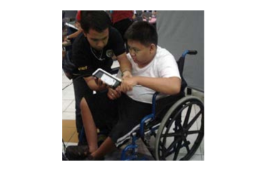 A young man who uses a wheelchair uses a biometric voter registration machine in the Philippines