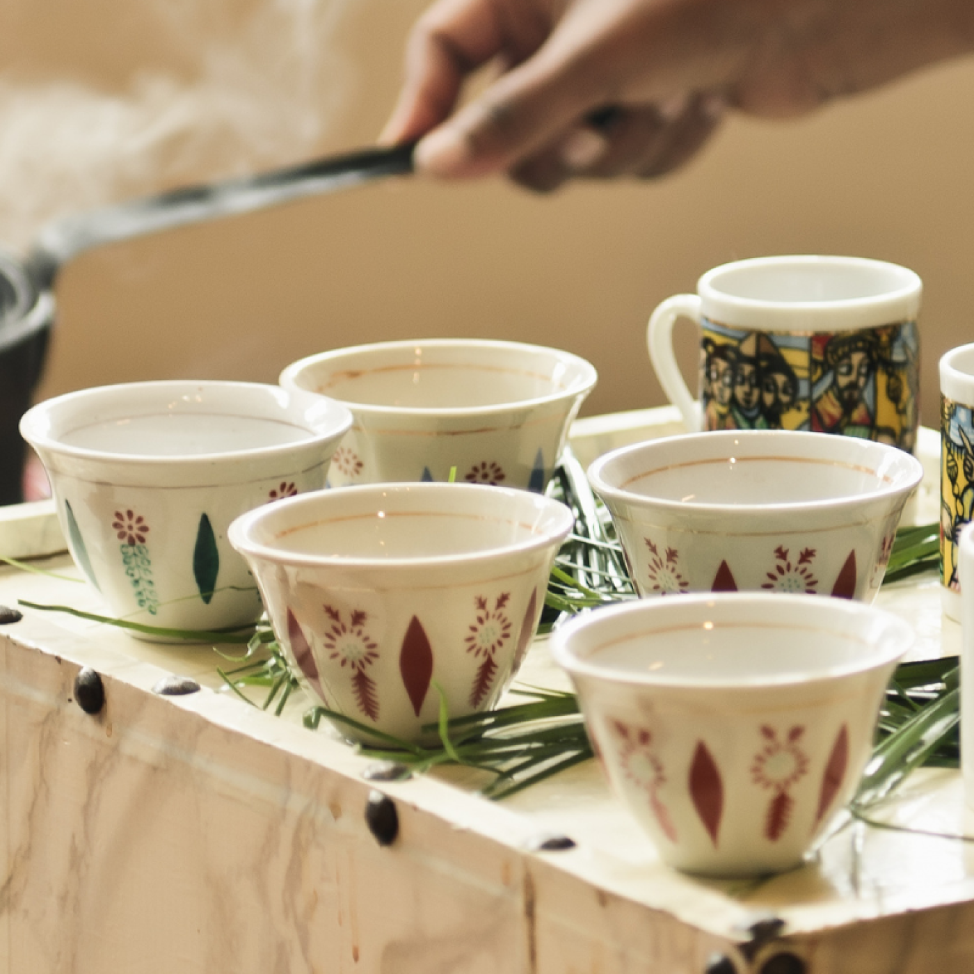 Hands preparing traditional Ethiopian coffee Ceremony with cups and steaming pot.