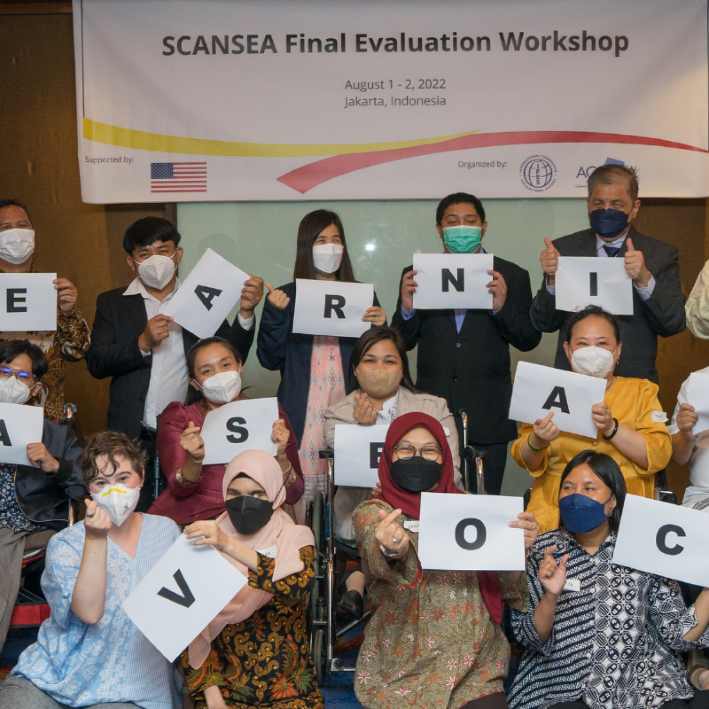 AGENDA Evaluation Event, participants hold letters in front of sign. 