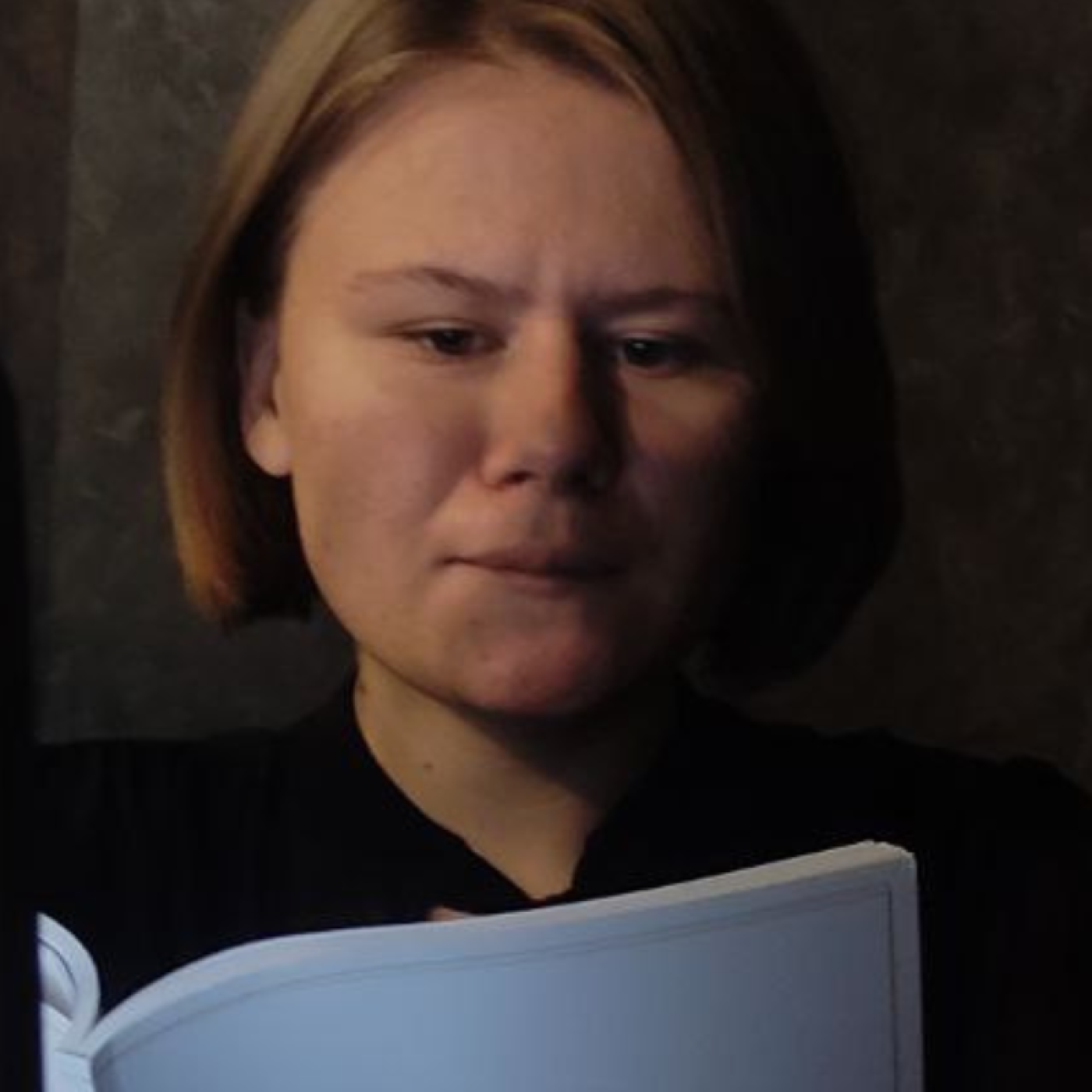 Anastasiia’s in a dark room reading.