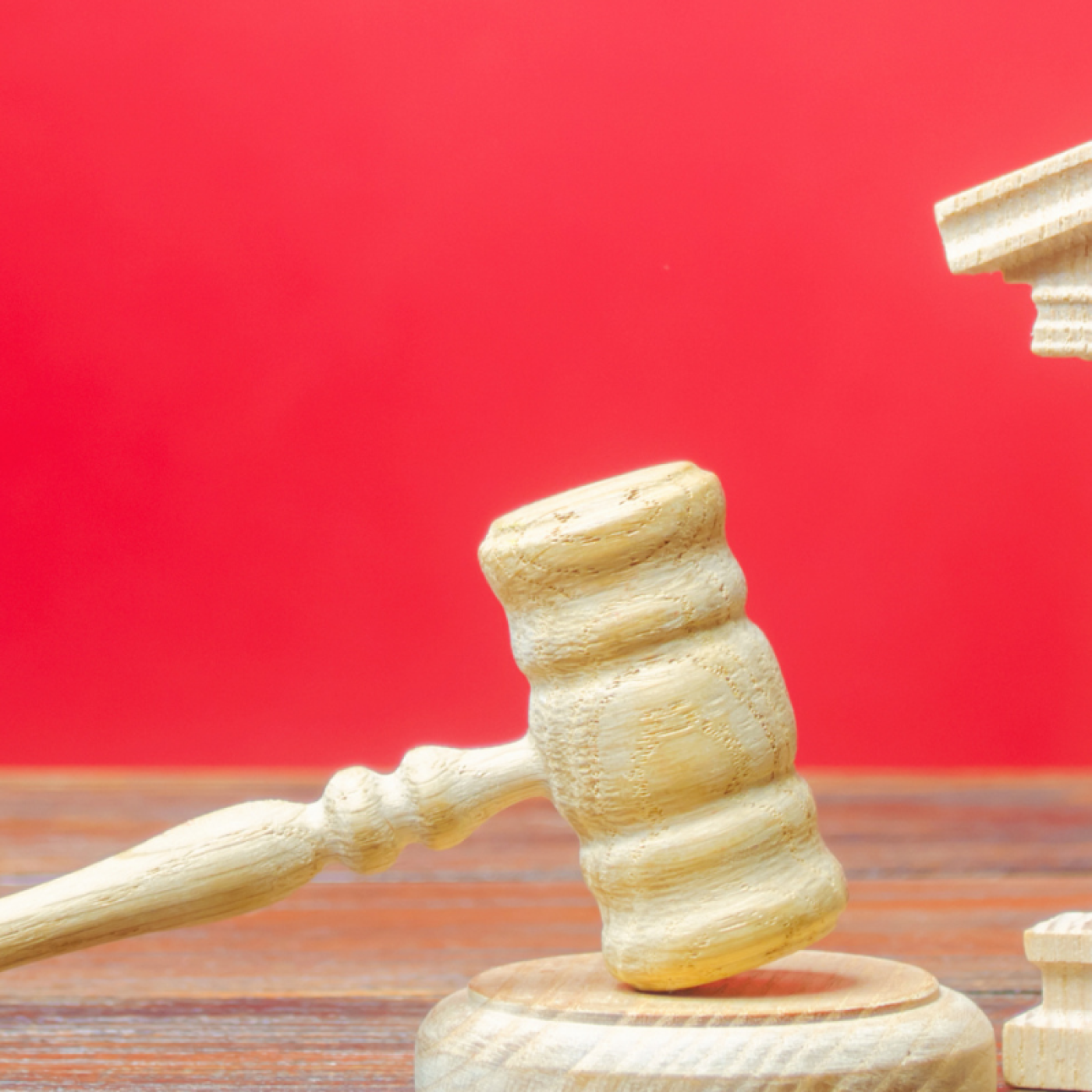 red background, wooden toy structure of a government building, wooden toy gavel.