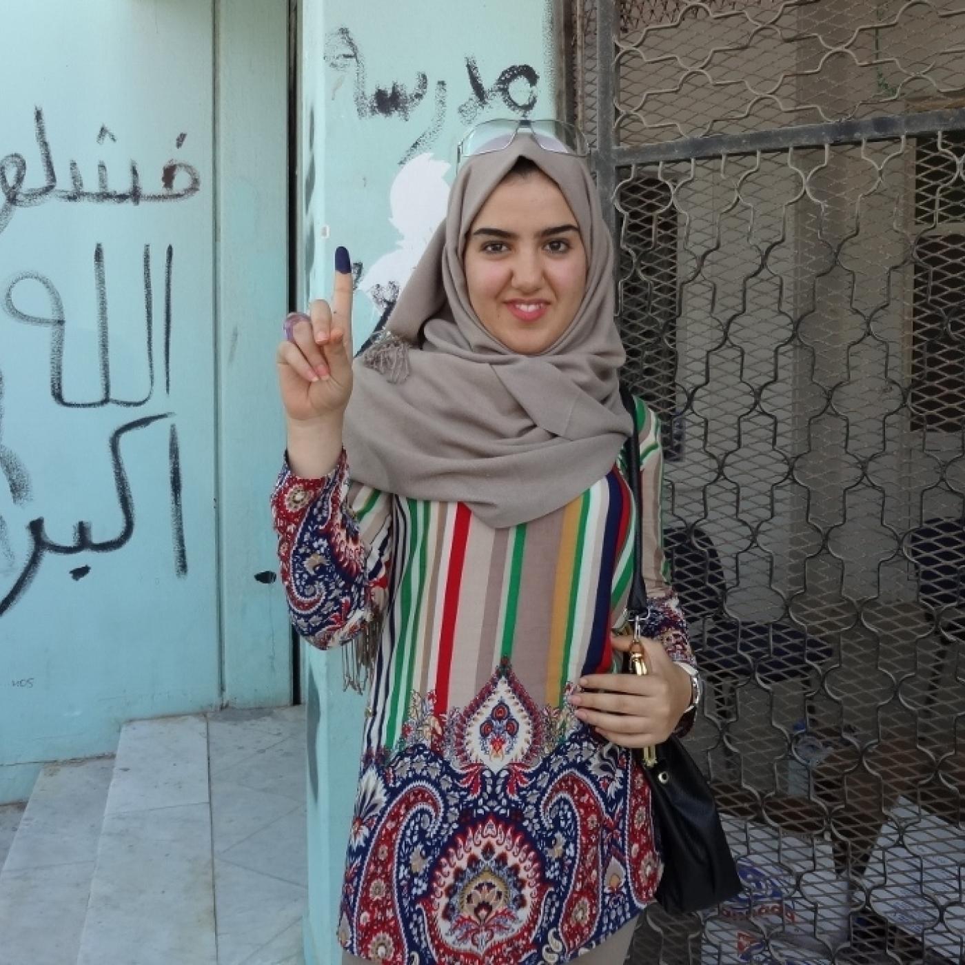 Libyan woman displays finger with indelible ink after casting a ballot.